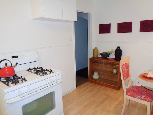 kitchen with white cabinetry, white gas range oven, and light hardwood / wood-style flooring