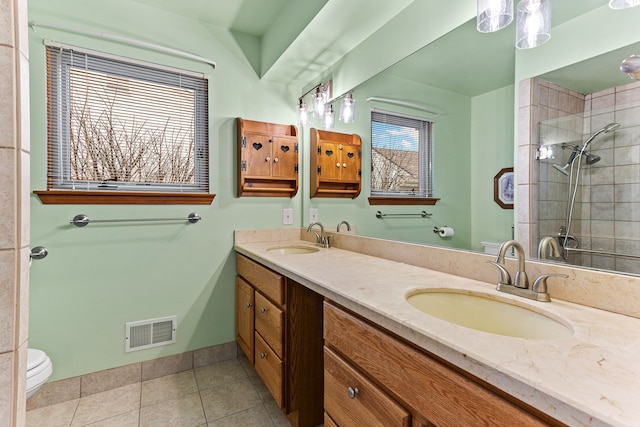 bathroom with tile patterned floors, toilet, vanity, and a tile shower