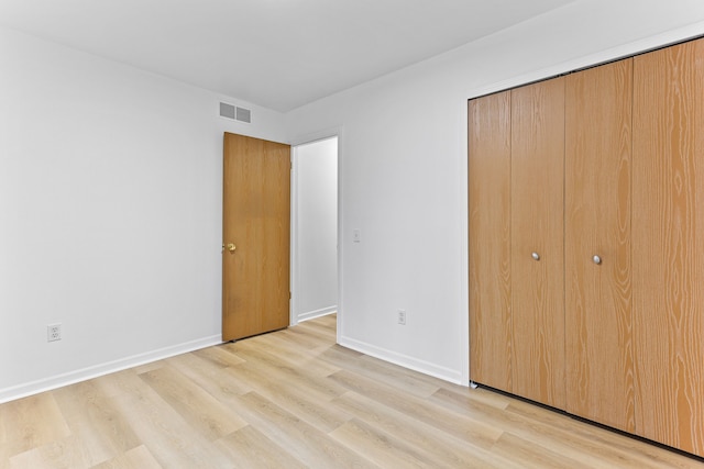 unfurnished bedroom featuring light wood-type flooring and a closet