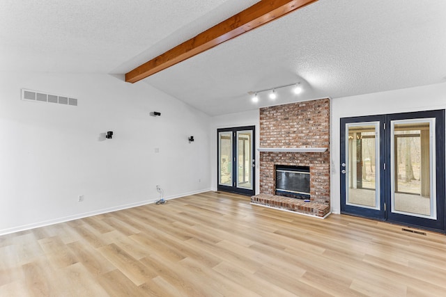 unfurnished living room with french doors, light hardwood / wood-style floors, a textured ceiling, and vaulted ceiling with beams