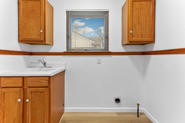 washroom with cabinets, sink, hookup for an electric dryer, and light hardwood / wood-style floors