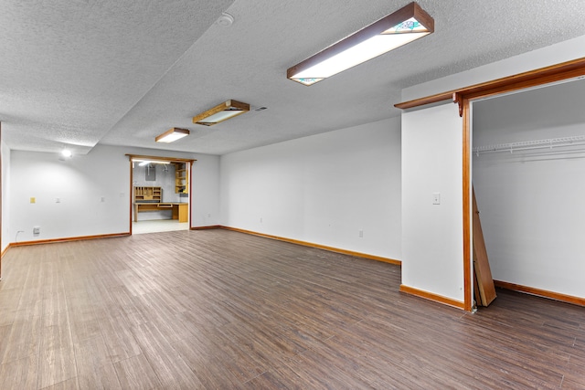 basement featuring a textured ceiling and dark hardwood / wood-style flooring