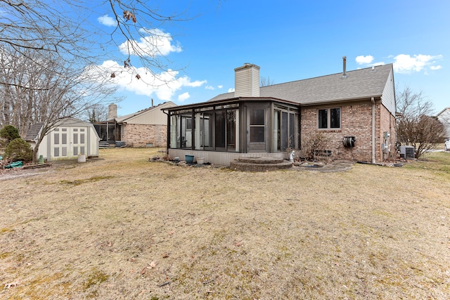 back of property featuring cooling unit, a lawn, a sunroom, and a shed