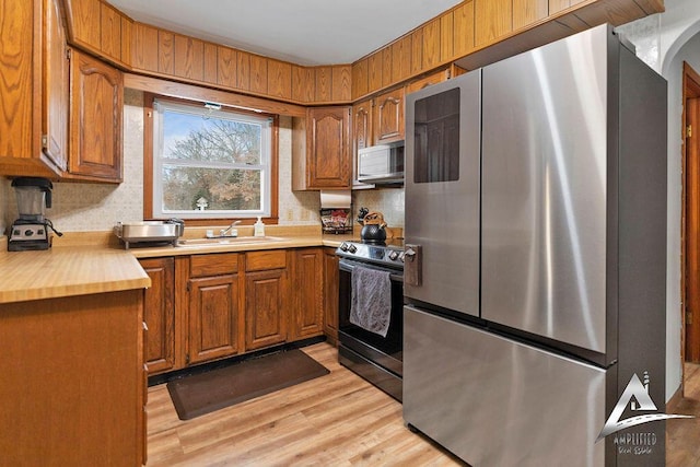 kitchen with stainless steel appliances, sink, and light hardwood / wood-style flooring