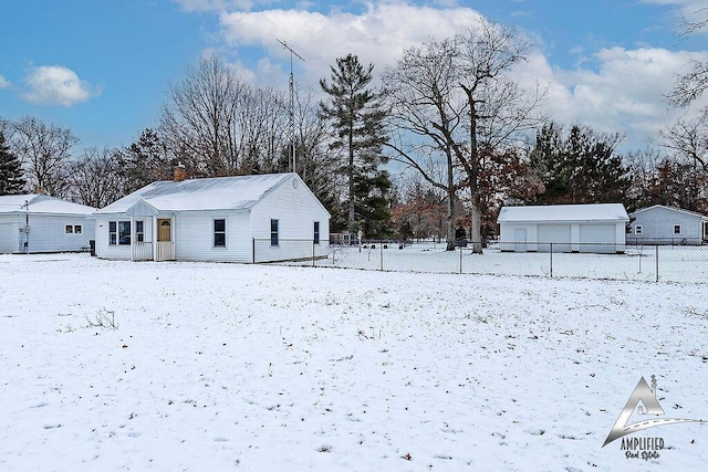 yard layered in snow with a garage and an outbuilding