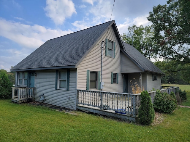 rear view of house featuring a wooden deck and a yard