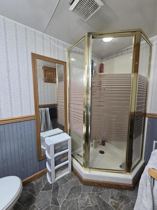 bathroom with a shower with door and toilet