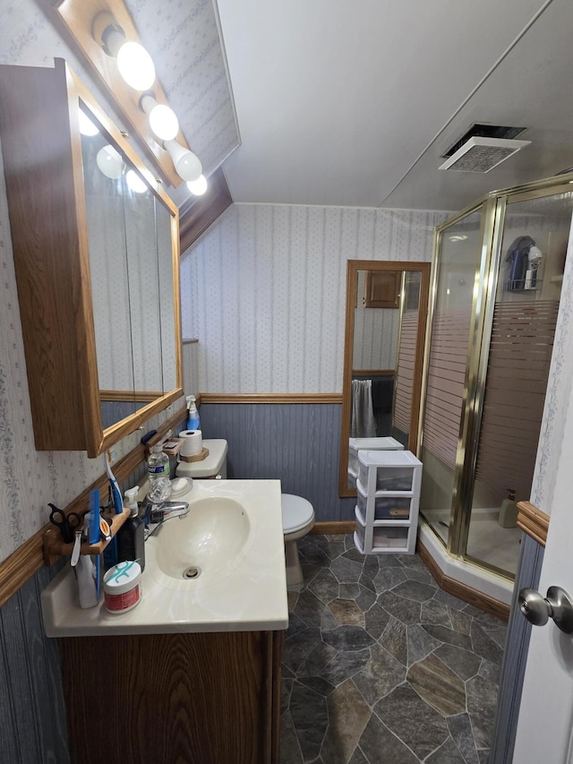 bathroom featuring vanity, a shower with shower door, and toilet