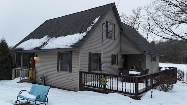 snow covered back of property with a deck