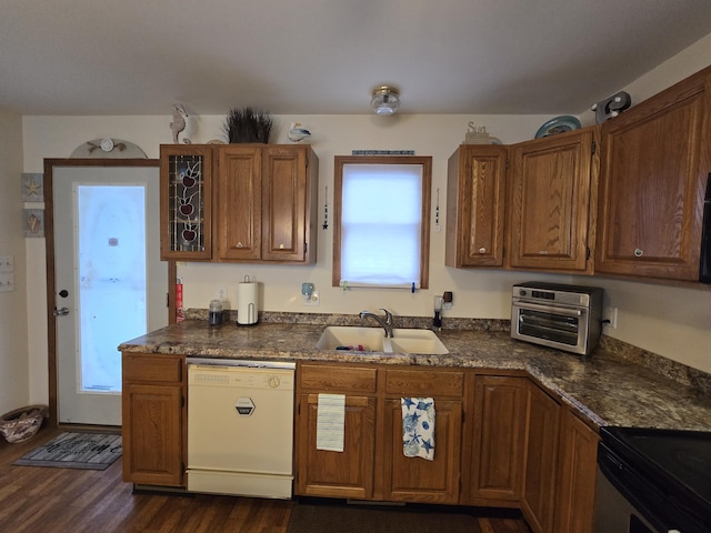 kitchen featuring white dishwasher, sink, dark wood-type flooring, and dark stone countertops