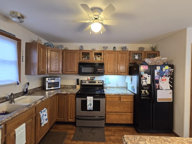 kitchen with dark hardwood / wood-style floors, sink, dark stone countertops, ceiling fan, and black appliances