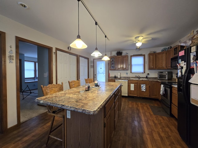 kitchen featuring sink, hanging light fixtures, a center island, black appliances, and a kitchen bar