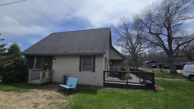 rear view of house with a yard, a deck, and a shingled roof