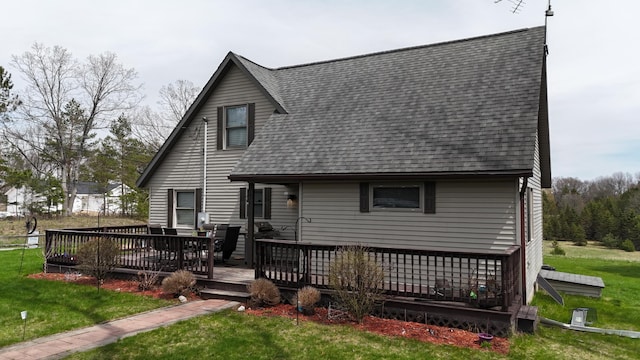 back of house featuring a yard, a deck, and a shingled roof