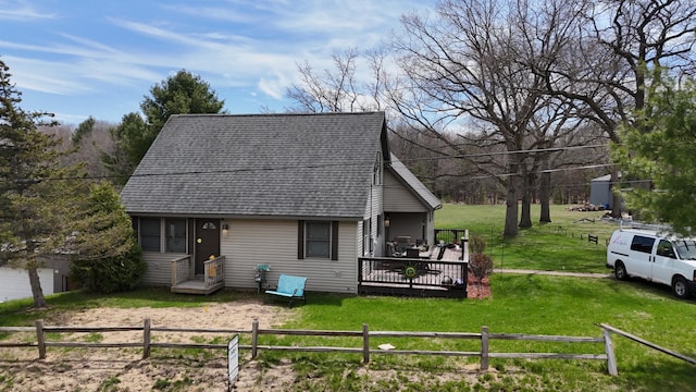 exterior space with a yard, a wooden deck, roof with shingles, and fence
