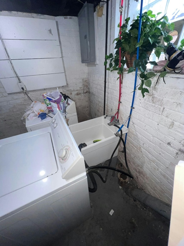 laundry room featuring separate washer and dryer, brick wall, and electric panel