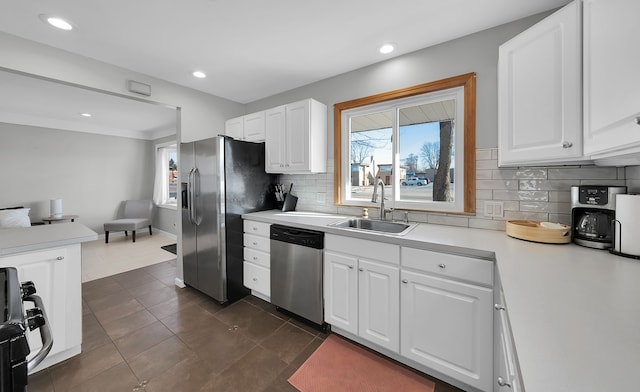 kitchen with tasteful backsplash, sink, white cabinets, and appliances with stainless steel finishes