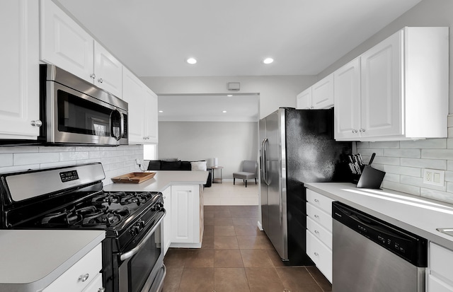 kitchen featuring white cabinetry, tasteful backsplash, appliances with stainless steel finishes, kitchen peninsula, and dark tile patterned flooring