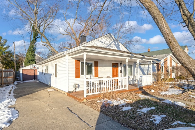 bungalow with a porch, a garage, and an outbuilding