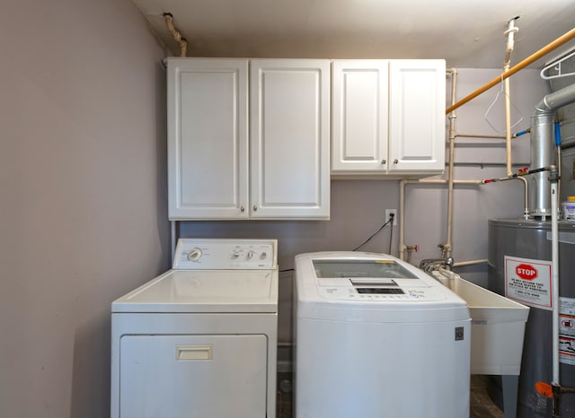 washroom with independent washer and dryer, sink, cabinets, and water heater