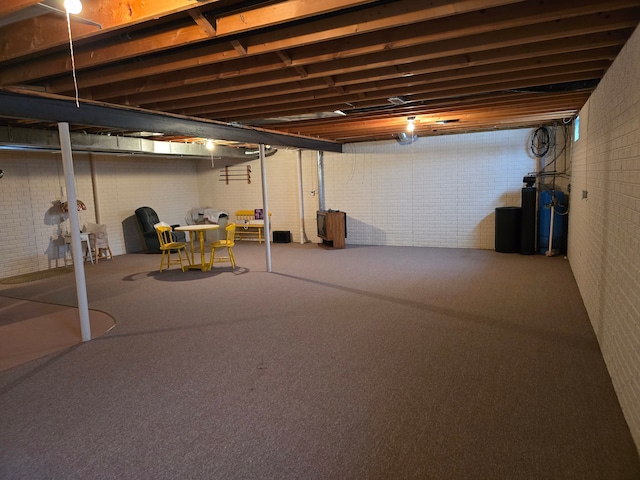 basement featuring brick wall and carpet flooring