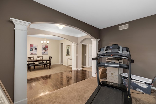 workout room featuring crown molding, hardwood / wood-style floors, and ornate columns