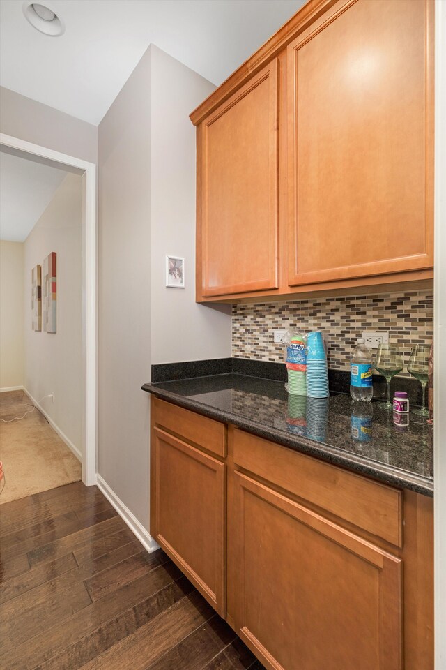 kitchen featuring dark stone countertops, decorative backsplash, and dark hardwood / wood-style floors