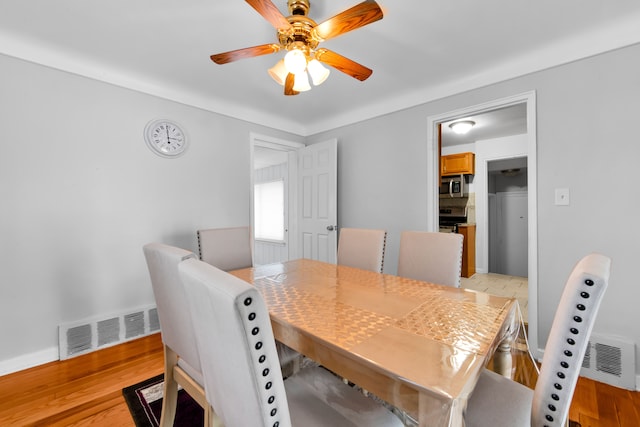 dining area with light wood-type flooring, baseboards, visible vents, and a ceiling fan