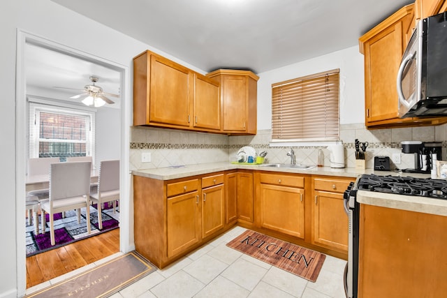 kitchen featuring light tile patterned floors, brown cabinets, stainless steel appliances, light countertops, and a sink