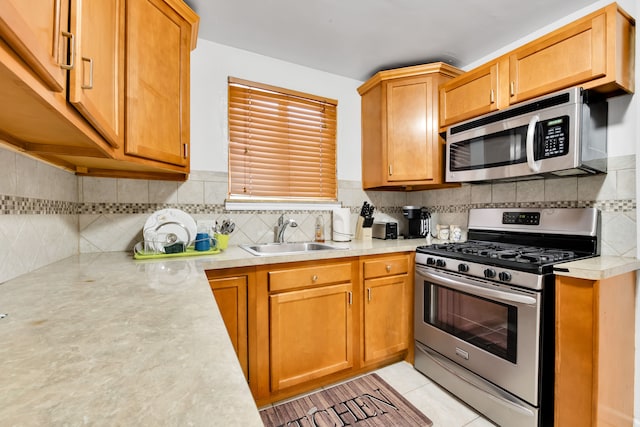 kitchen featuring light tile patterned floors, a sink, light countertops, appliances with stainless steel finishes, and tasteful backsplash