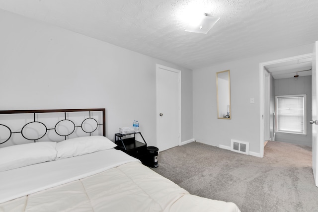 carpeted bedroom with visible vents, a textured ceiling, and baseboards