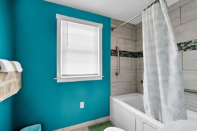 bathroom featuring toilet, shower / tub combo, and baseboards