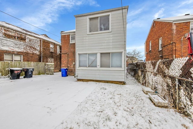 snow covered property with fence private yard and brick siding