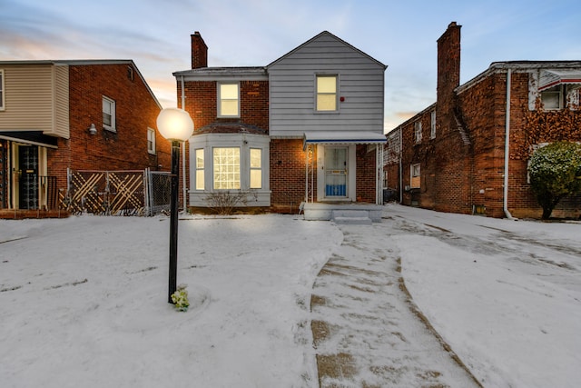 view of front of property with brick siding, fence, and a chimney