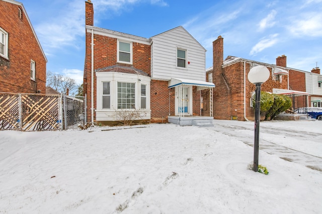 view of front of home featuring a chimney, fence, and brick siding