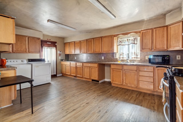 kitchen with sink, washer and clothes dryer, tasteful backsplash, light hardwood / wood-style floors, and stainless steel range oven