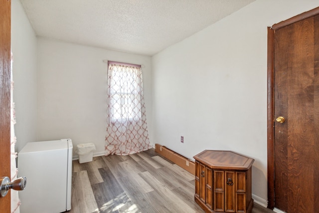 spare room featuring light hardwood / wood-style flooring and a textured ceiling