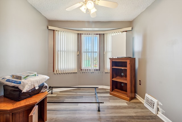 bedroom with ceiling fan, hardwood / wood-style floors, and a textured ceiling