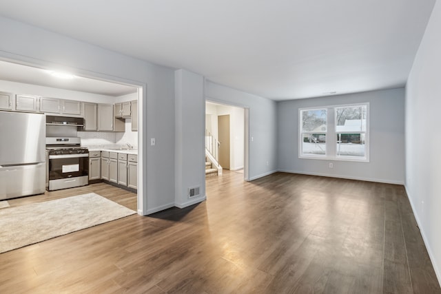 interior space featuring sink, dark wood-type flooring, gray cabinets, stainless steel appliances, and tasteful backsplash