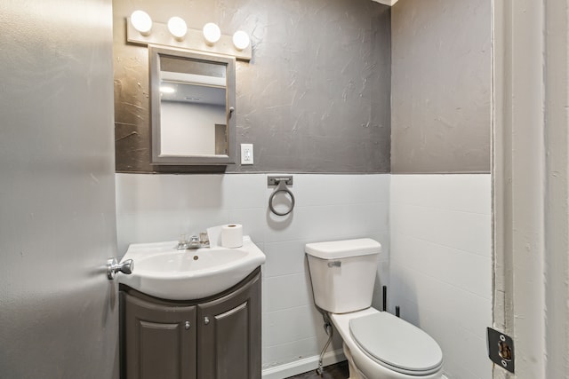 bathroom featuring vanity, tile walls, and toilet