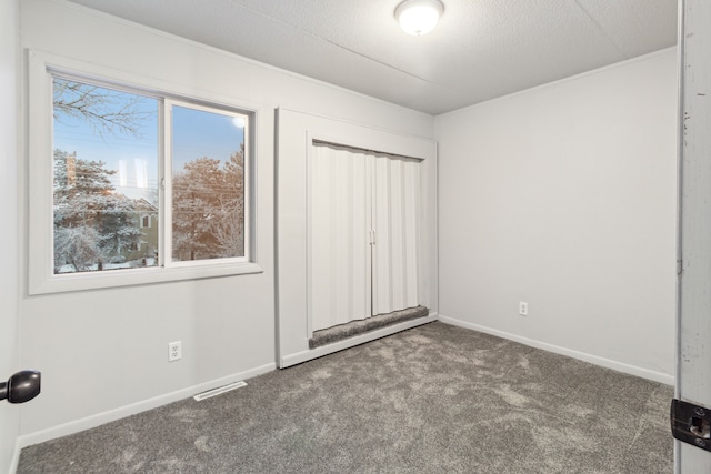 unfurnished bedroom featuring a textured ceiling and dark carpet