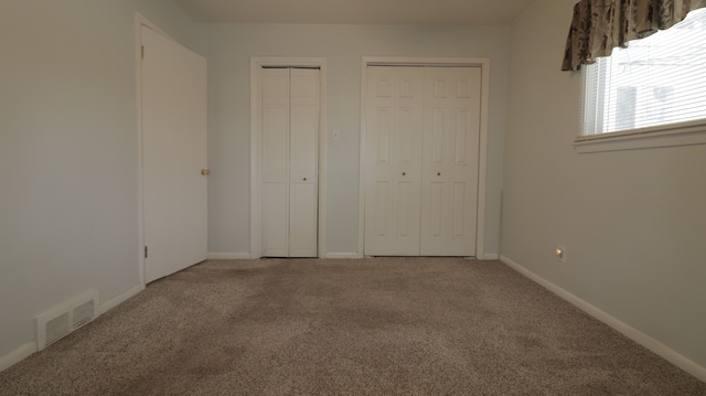 unfurnished bedroom featuring carpet floors and two closets