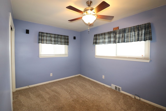 spare room with ceiling fan, a healthy amount of sunlight, and carpet