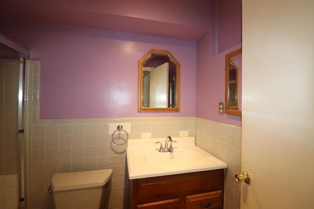 bathroom with vanity, tile walls, and toilet