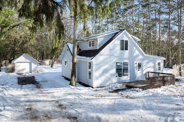 snow covered property featuring an outbuilding, a garage, and a deck