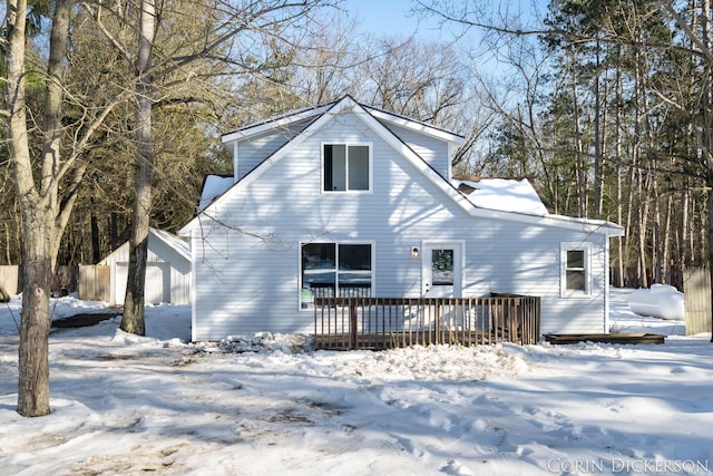 snow covered back of property featuring a wooden deck