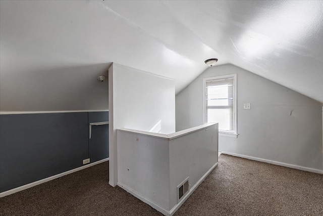 additional living space featuring vaulted ceiling and dark colored carpet