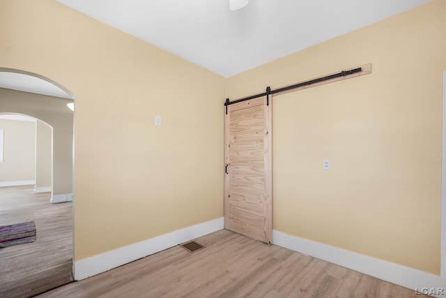 unfurnished room featuring a barn door and light wood-type flooring