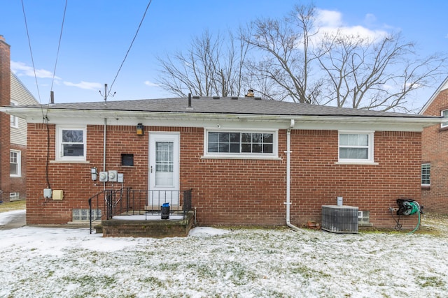 snow covered rear of property featuring central air condition unit