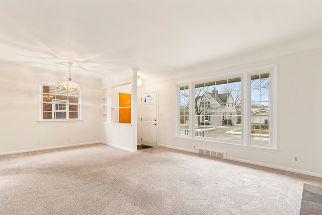 carpeted empty room featuring an inviting chandelier and built in features